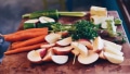 Bio-Lebensmittel: Geschnittene Äpfel, Karotten und Gurken auf einem Holzbrett