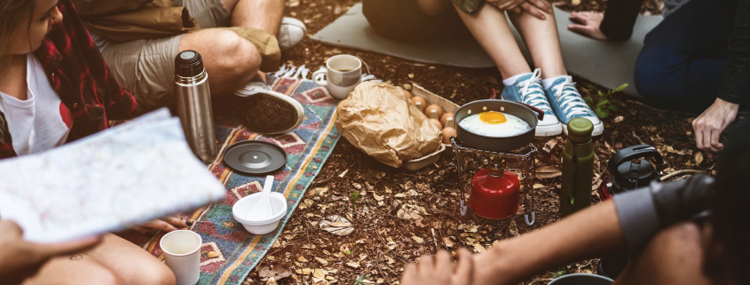 Menschen frühstücken vor einem Zelt