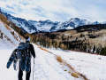 Ein Mensch mit Schneeschuhen am Rucksack wandert durch winterliche Landschaft